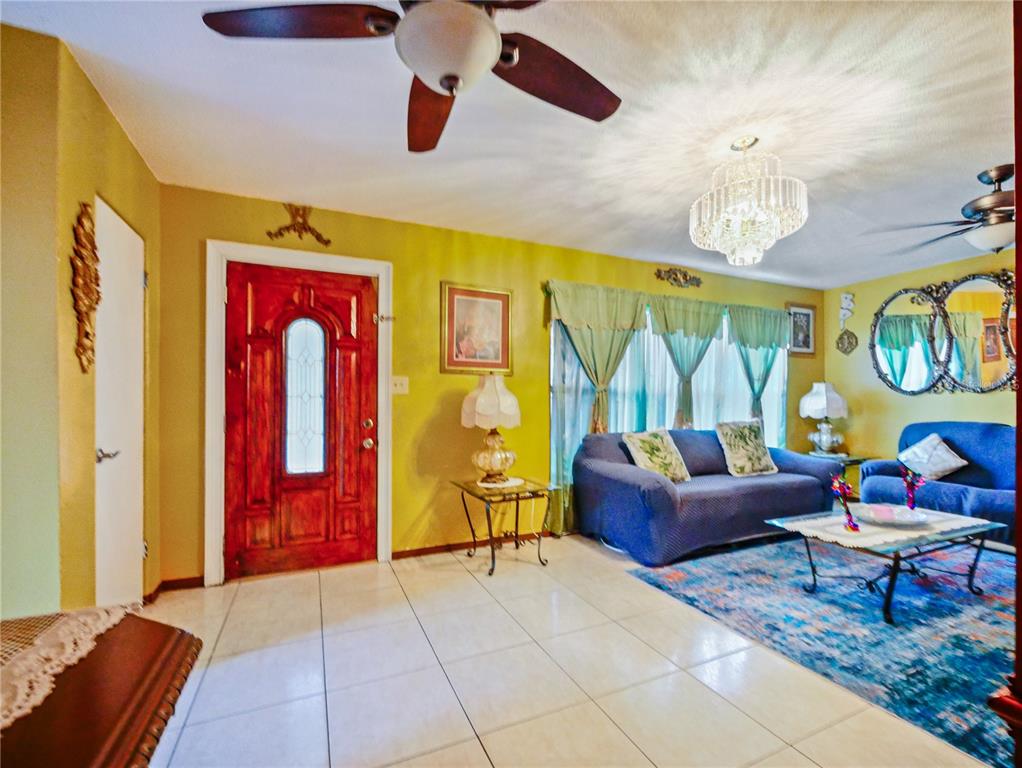 A living room features yellow walls, tile flooring, a red front door, and blue sofas — 4912 DANNY BOY CIRCLE, ORLANDO, FL
