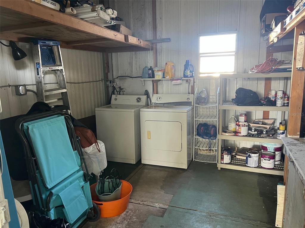 A utility room features a washer, dryer, metal shelving, and a folding chair — 29250 US HIGHWAY 19 N UNIT 570, CLEARWATER, FL