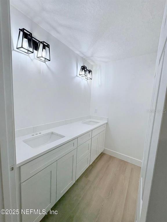 A bathroom features a double vanity with white cabinets, a white countertop, and two light fixtures — 1264 CORAL FARMS ROAD, FLORAHOME, FL