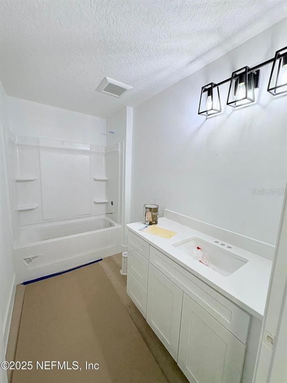 A bathroom features a white vanity with a sink, a bathtub, and modern light fixtures — 1264 CORAL FARMS ROAD, FLORAHOME, FL