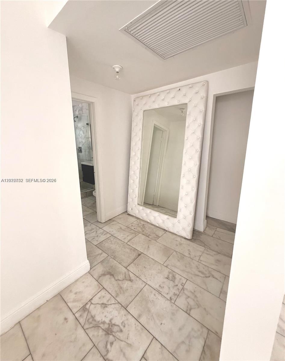 A hallway with marble tile flooring features a large tufted white-framed floor mirror — 922 Jefferson Ave # 6, Miami Beach FL 33139, MIAMI BEACH, FL