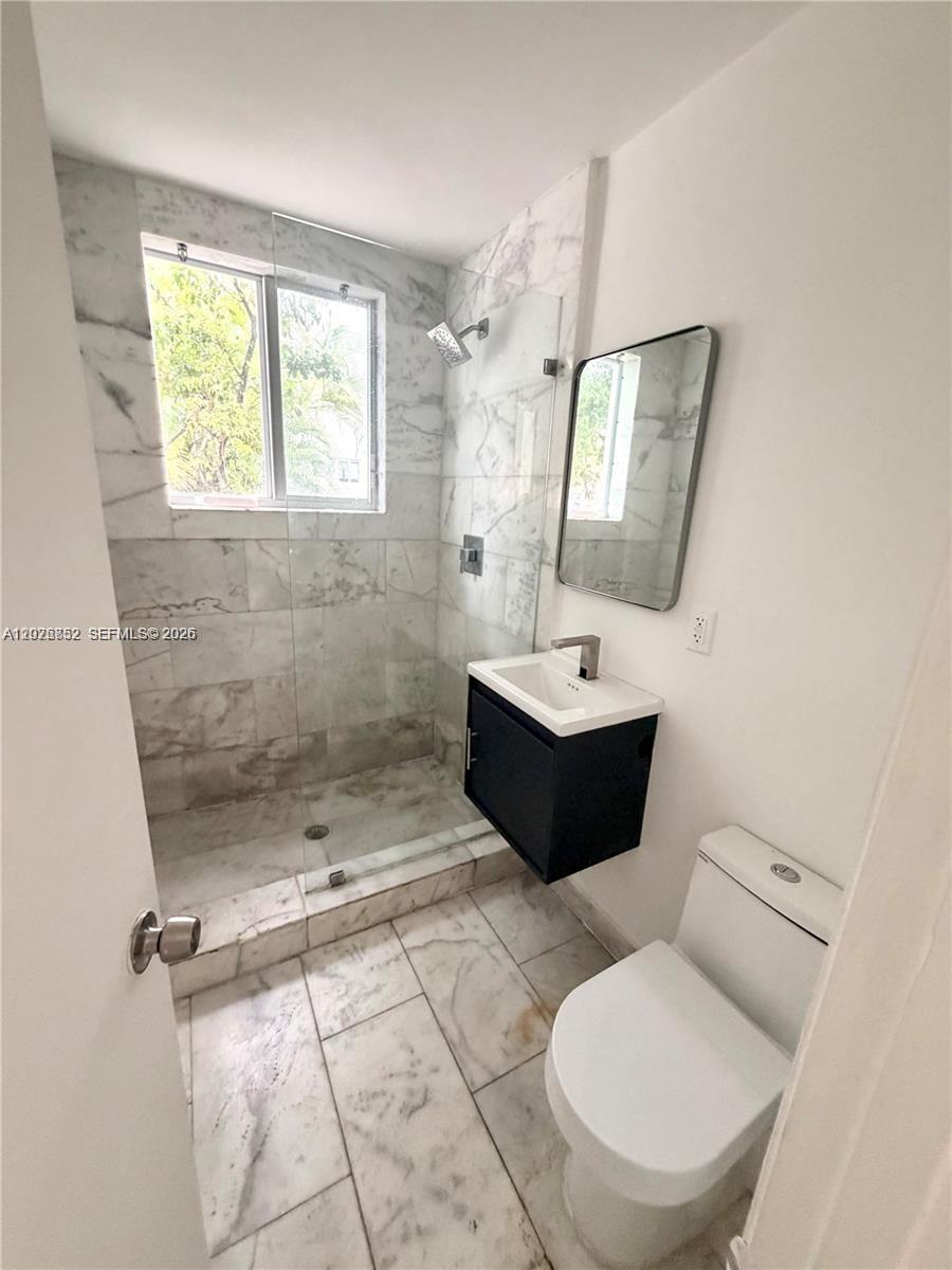 A bathroom features a walk-in shower with marble tile, a floating vanity, and a toilet — 922 Jefferson Ave # 6, Miami Beach FL 33139, MIAMI BEACH, FL