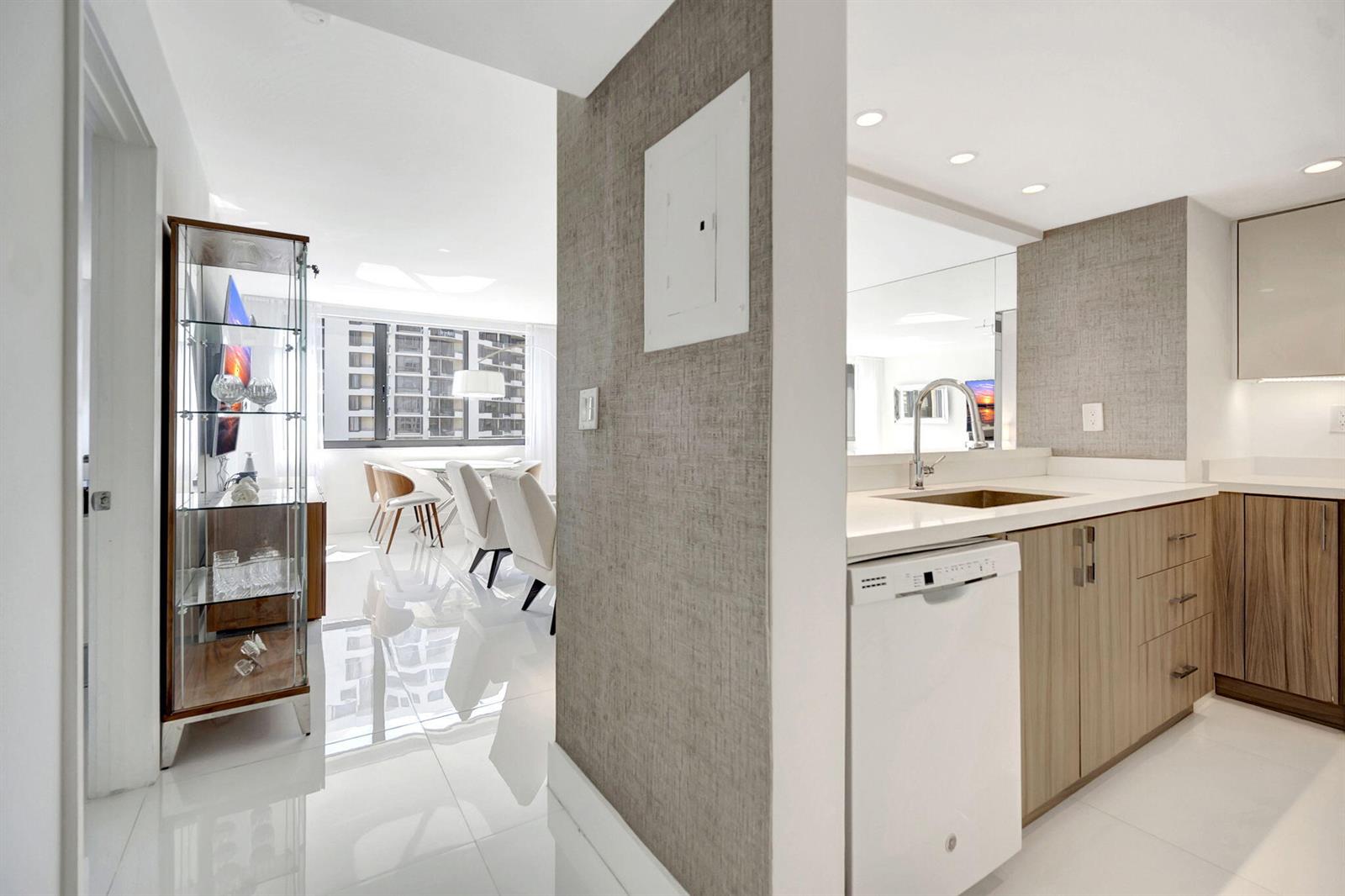 A kitchen with light wood cabinets and a white dishwasher opens to a dining area — 540 Brickell Key Drive # 919, Miami FL 33131, MIAMI, FL