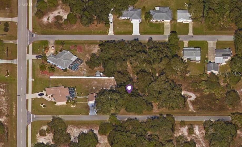 This aerial view shows a wooded residential lot situated between two houses and two streets — 21460 ARGOSY AVENUE, PORT CHARLOTTE, FL