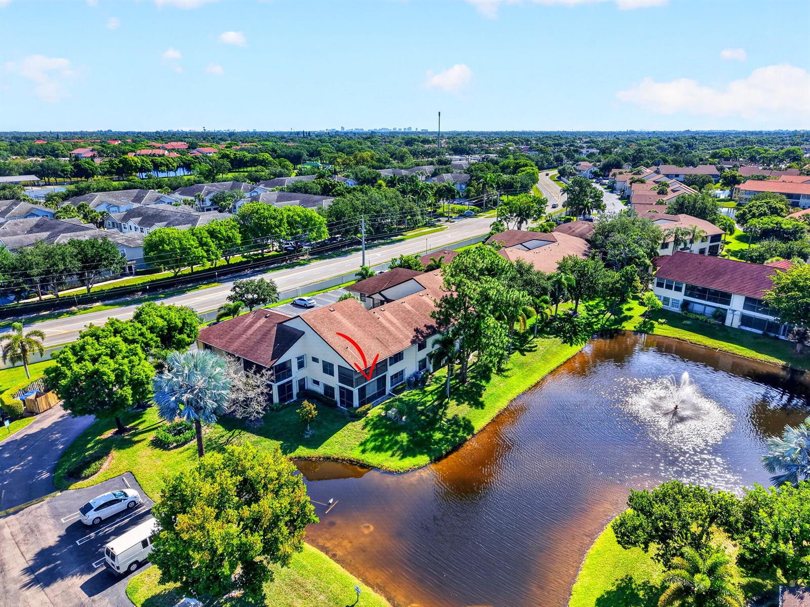 An aerial view of a multi-story apartment building next to a pond with a fountain — 3281 Jog Park Drive, FL 33467, FL