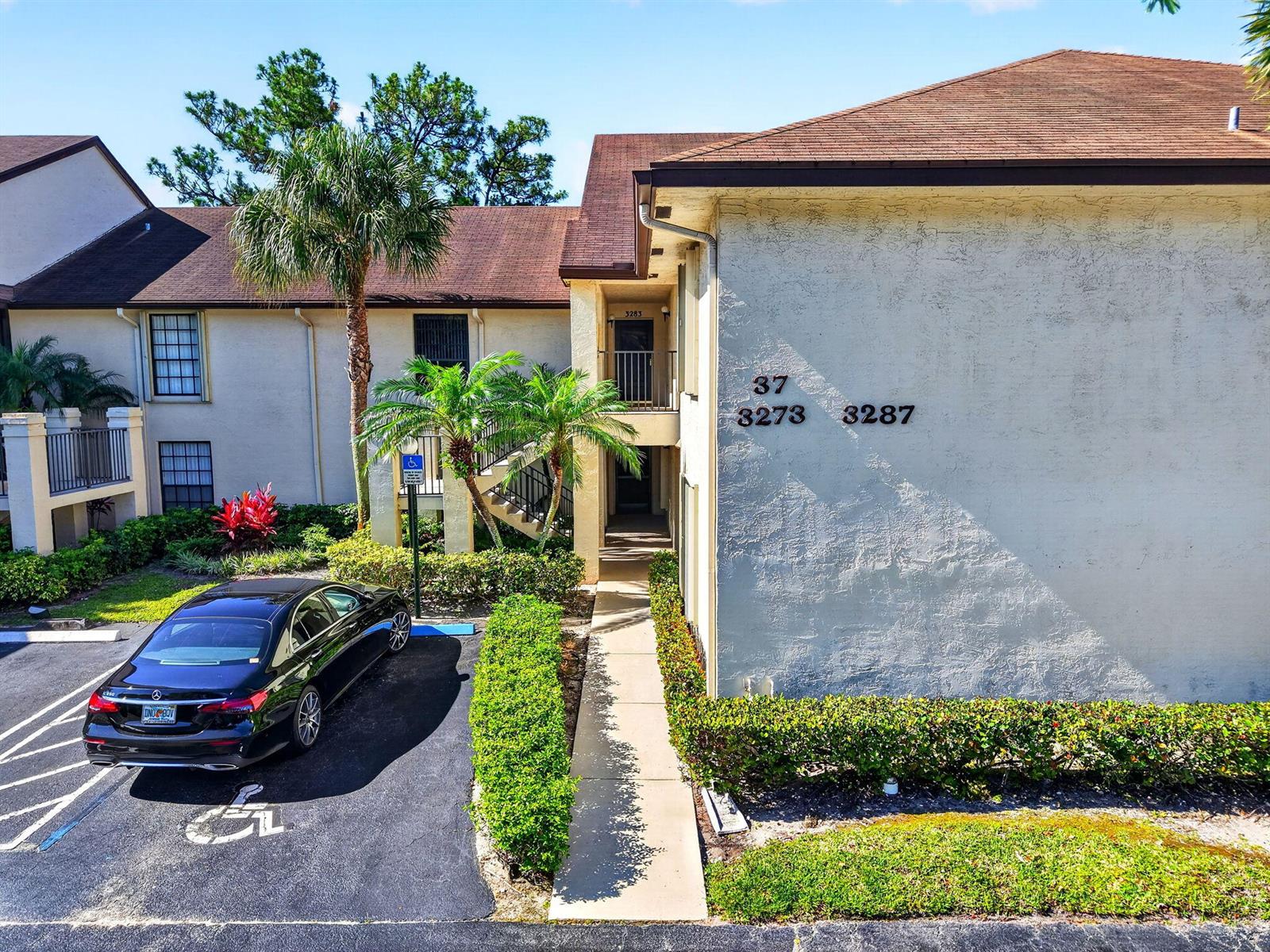 An exterior view of a multi-story apartment building with a handicap parking space — 3281 Jog Park Drive, FL 33467, FL