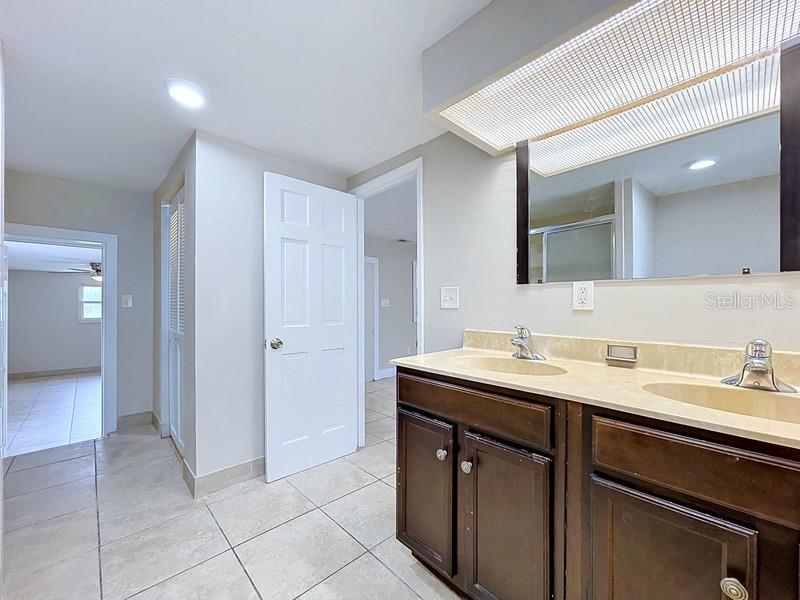 A bathroom features a double-sink vanity with dark wood cabinets and light-colored tile flooring — 7018 54TH AVENUE N, ST PETERSBURG, FL