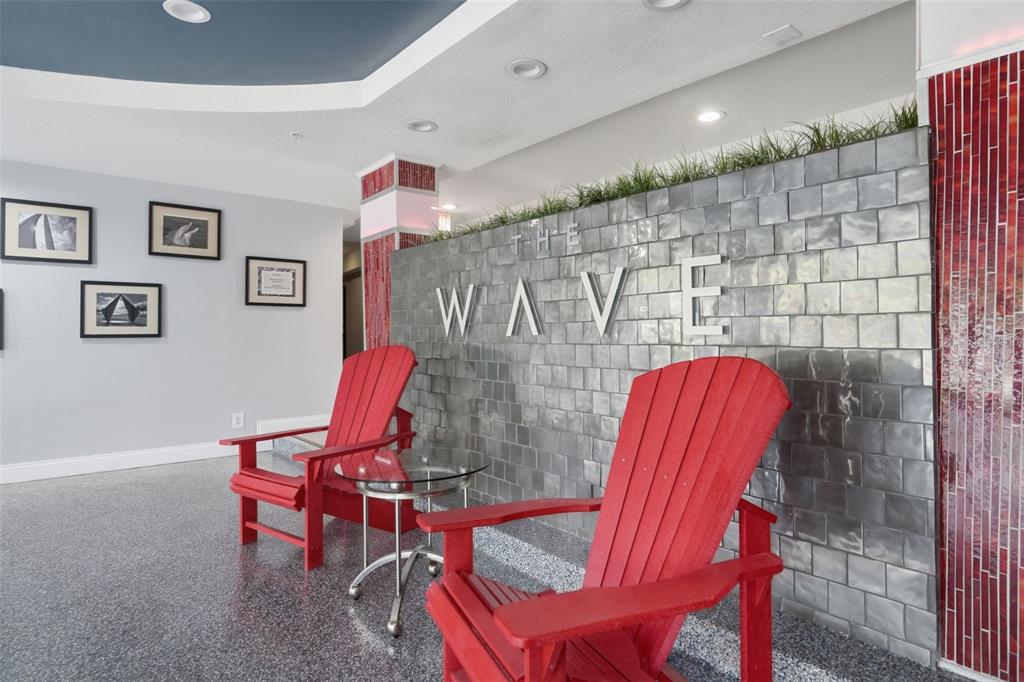 Two red Adirondack chairs sit in a lobby with a tiled wall labeled The Wave — 3315 58TH AVENUE S UNIT 617, ST PETERSBURG, FL