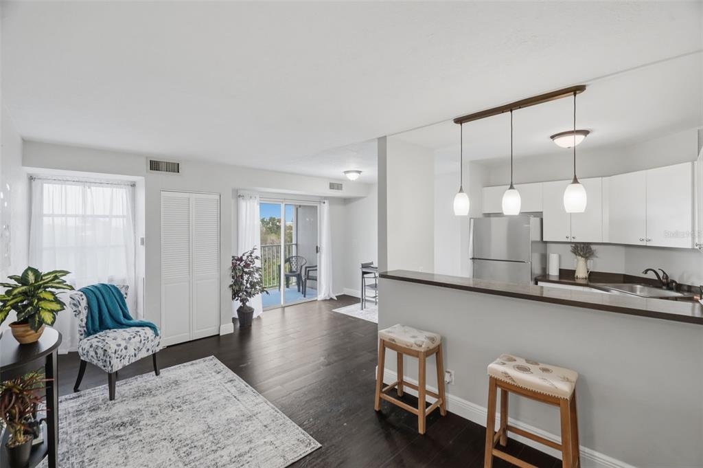 A living room with dark wood floors, a breakfast bar, and a balcony view — 3315 58TH AVENUE S UNIT 617, ST PETERSBURG, FL