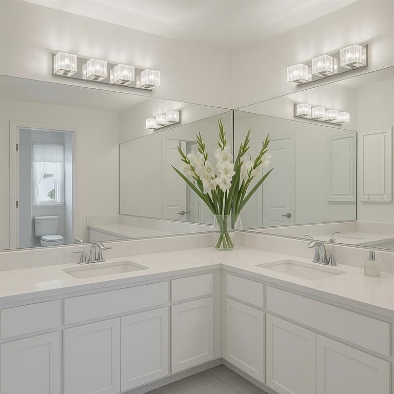 A bright bathroom features a corner vanity with white cabinets, quartz countertops, and dual sinks — 23381 PEACHLAND BOULEVARD, PORT CHARLOTTE, FL