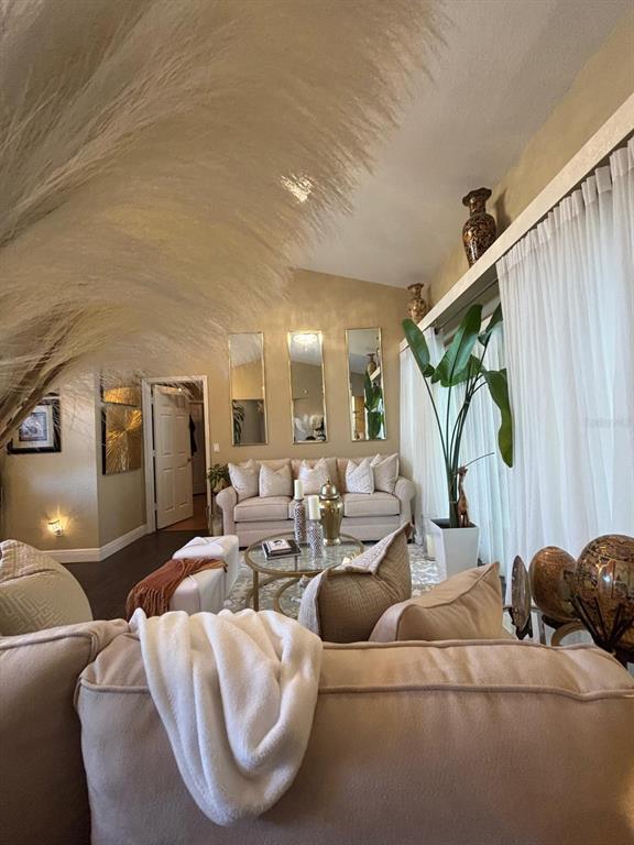 A living room features beige sofas, a glass coffee table, and three vertical wall mirrors — 23381 PEACHLAND BOULEVARD, PORT CHARLOTTE, FL
