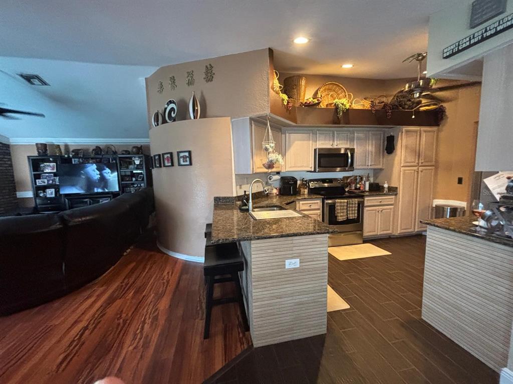 A kitchen with granite countertops and light cabinets opens to a living room with flooring — 23381 PEACHLAND BOULEVARD, PORT CHARLOTTE, FL
