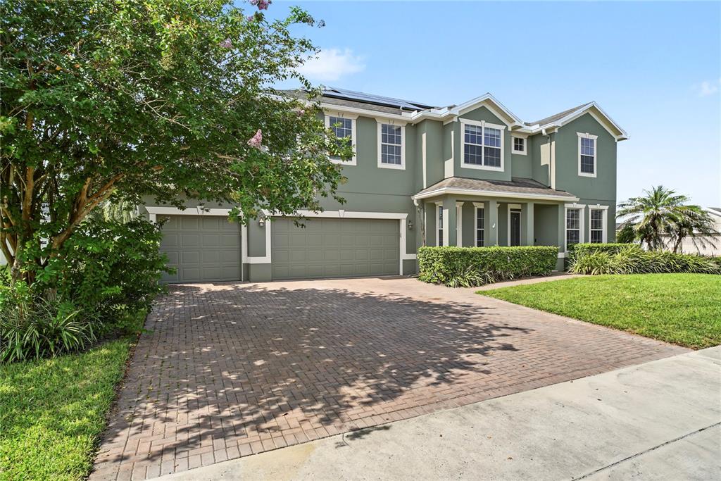 A two-story green house with a three-car garage and a brick paver driveway — 637 GRASSY STONE DRIVE, WINTER GARDEN, FL