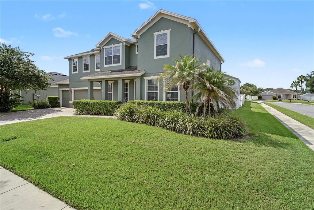 A two-story house with green siding, a front lawn, and a palm tree — 637 GRASSY STONE DRIVE, WINTER GARDEN, FL