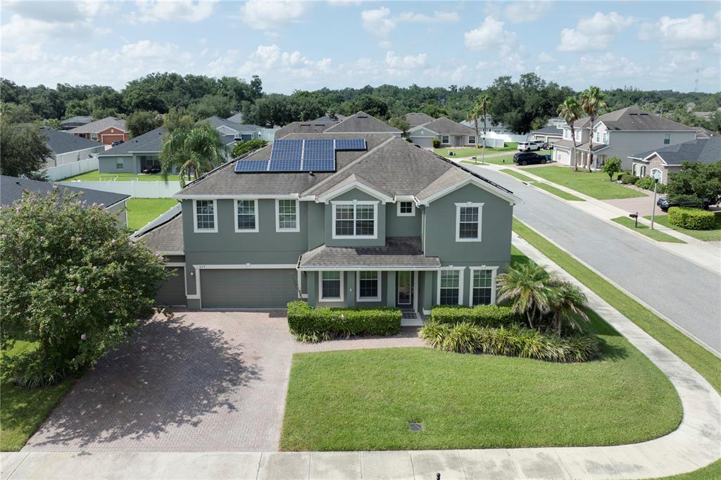 An aerial view shows a two-story green house with solar panels on the roof — 637 GRASSY STONE DRIVE, WINTER GARDEN, FL