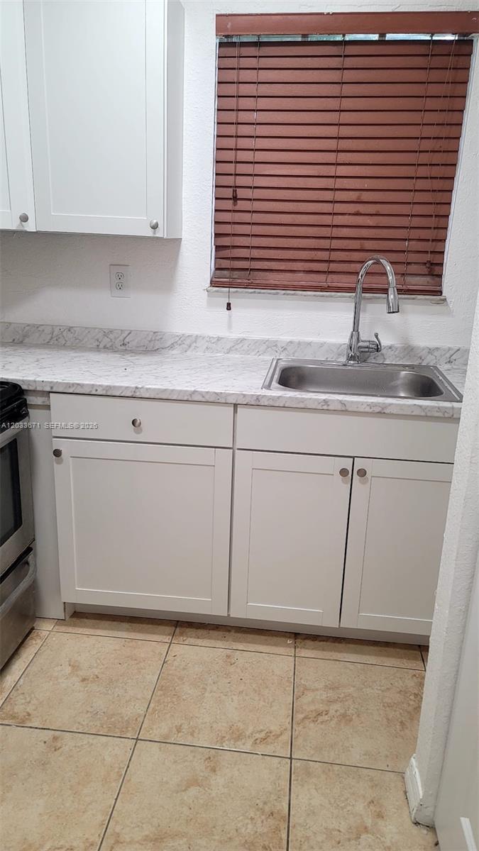 An empty room features white walls, tan tile flooring, a white door, and two windows — 3250 NW 94 ST # 0, Miami FL 33147, MIAMI, FL