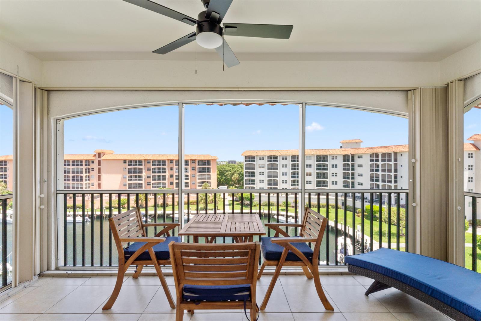A screened-in balcony features a wooden dining set, a lounge chair, and a water view — 2871 N Ocean Boulevard # M538, Boca Raton FL 33431, BOCA RATON, FL