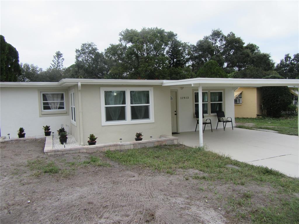 A single-story house with a white exterior, a carport, and a small front garden bed — 11913 104TH STREET, LARGO, FL