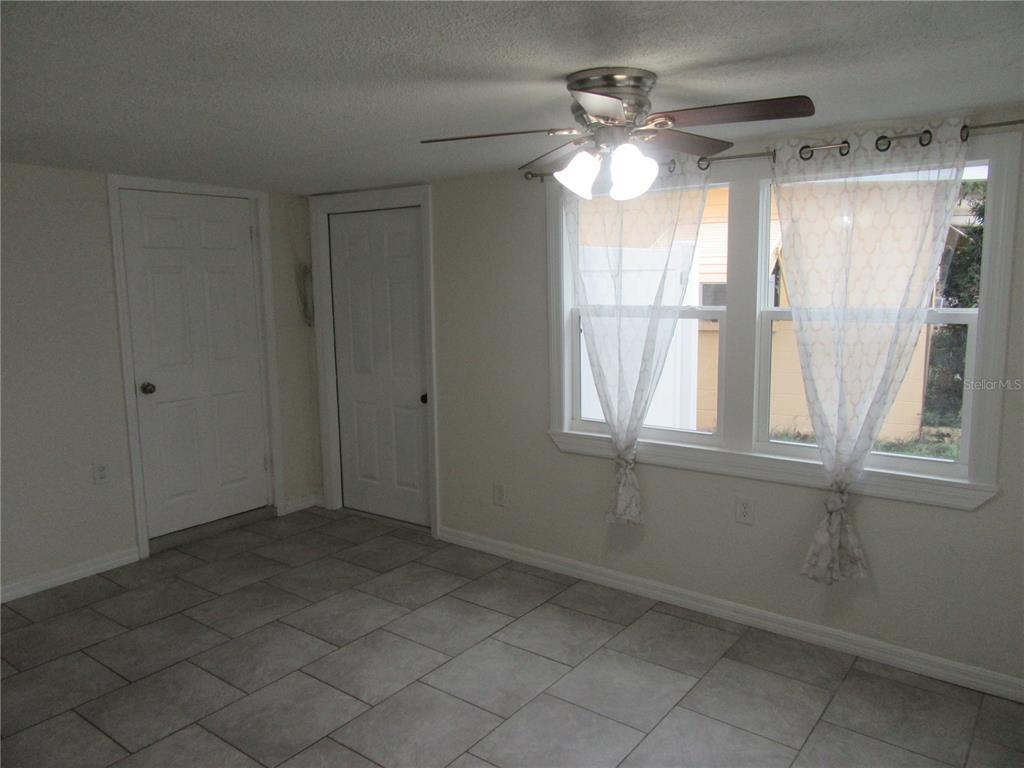 A room with light-colored walls, tiled flooring, a ceiling fan, and two windows with curtains — 11913 104TH STREET, LARGO, FL