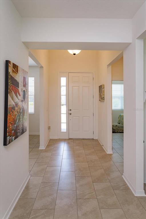 A tiled entryway features a white front door with a sidelight and a wall painting — 16707 SANCTUARY DRIVE, WINTER GARDEN, FL