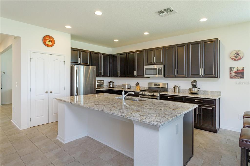 A kitchen with dark wood cabinets, granite countertops, a center island, and stainless steel appliances — 16707 SANCTUARY DRIVE, WINTER GARDEN, FL