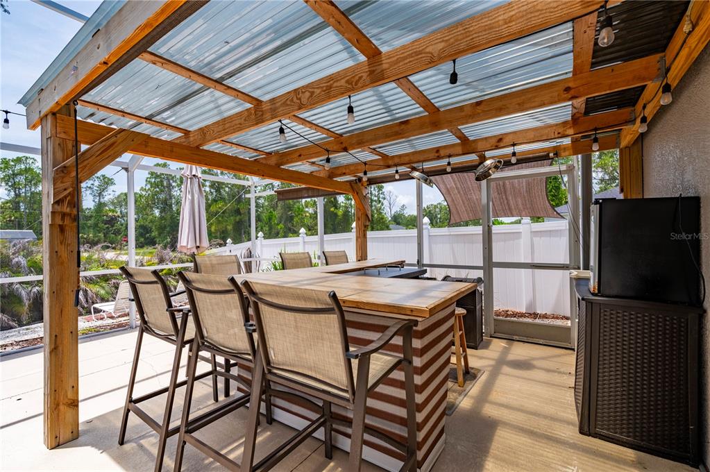 A covered outdoor patio features a bar with stools under a corrugated plastic roof — 5615 MOJAVE AVENUE, NORTH PORT, FL