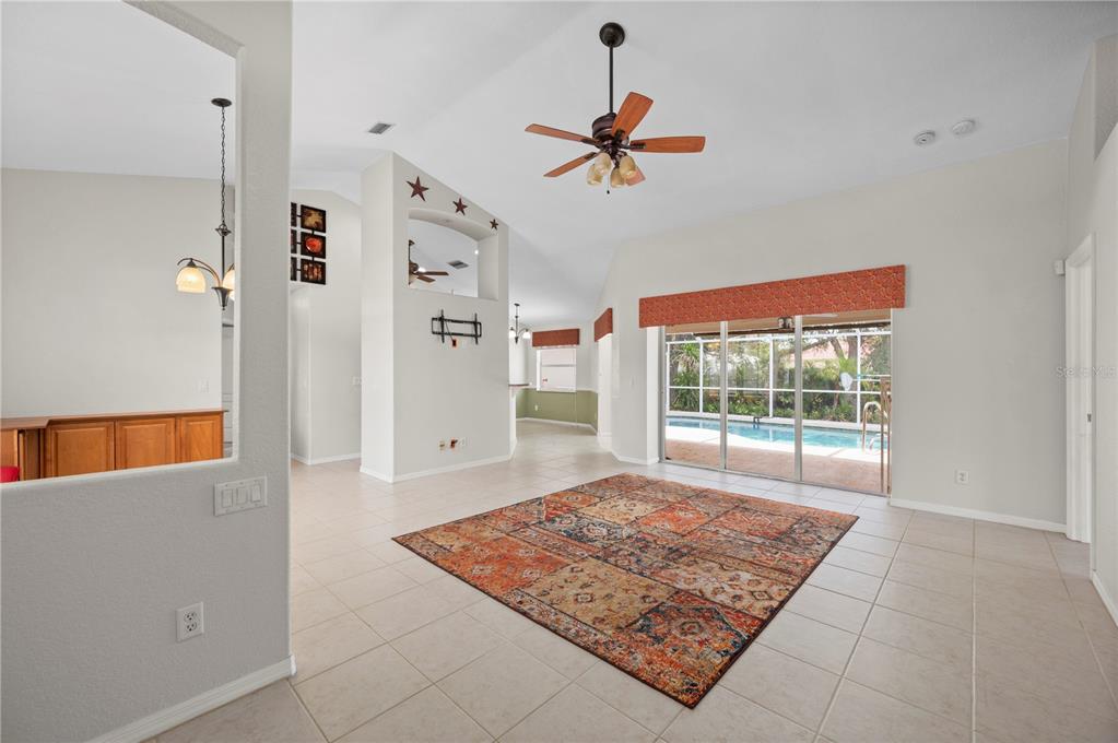 An open-concept living and dining area features tile floors, a leather sofa, and kitchen access — 5615 MOJAVE AVENUE, NORTH PORT, FL