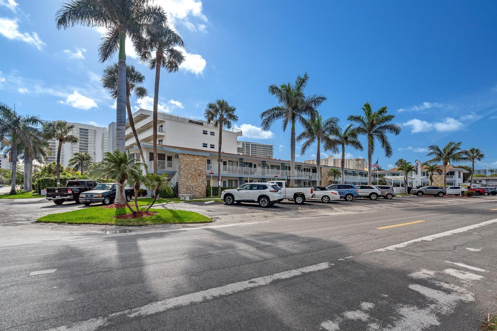 A multi-story apartment building with stone accents and palm trees sits behind a parking lot — 1110 N Riverside Drive # 20, Pompano Beach FL 33062, POMPANO BEACH, FL
