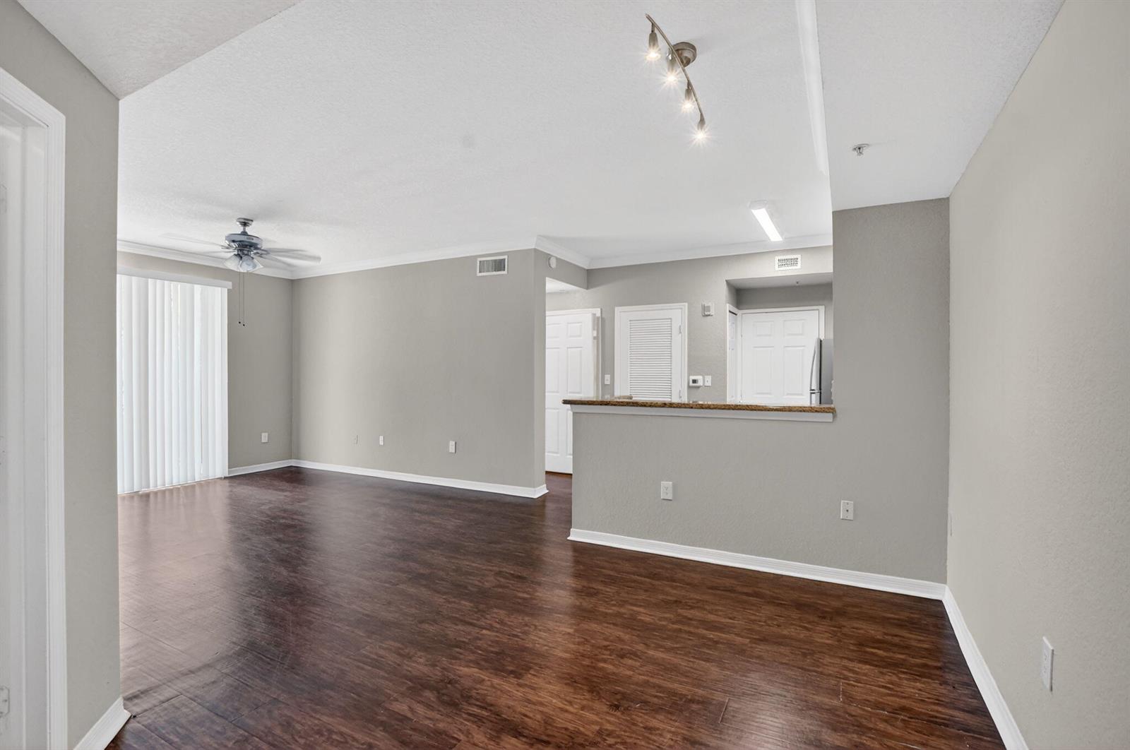An open-concept living area features dark wood-look flooring, gray walls, and a kitchen pass-through — 15085 Michelangelo Boulevard # 105, Delray Beach FL 33446, DELRAY BEACH, FL