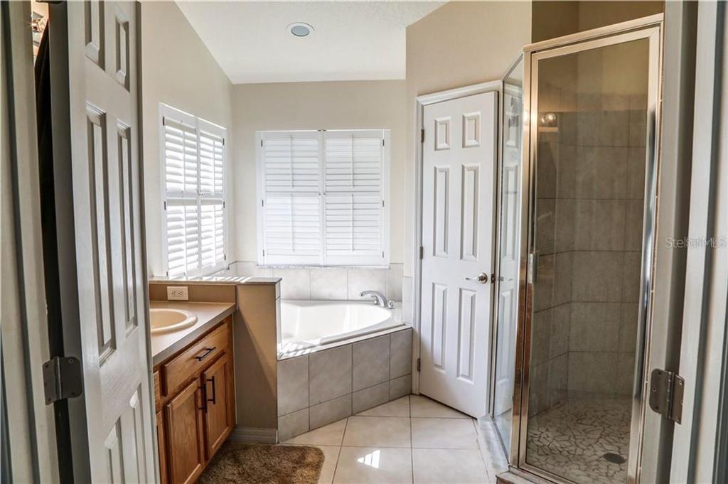 A bathroom features a corner soaking tub, a glass-enclosed shower, and a wooden vanity — 1521 ECHO LAKE COURT, ORLANDO, FL