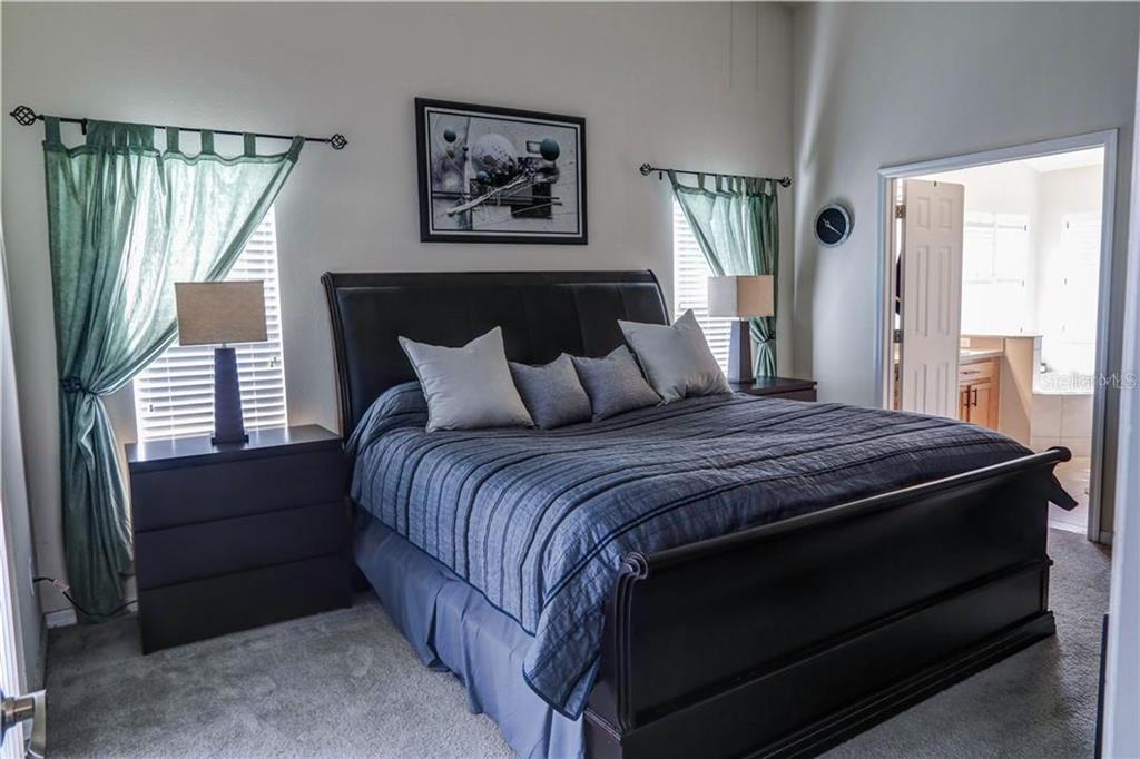 A bedroom features a dark wood sleigh bed, two nightstands with lamps, and green curtains — 1521 ECHO LAKE COURT, ORLANDO, FL