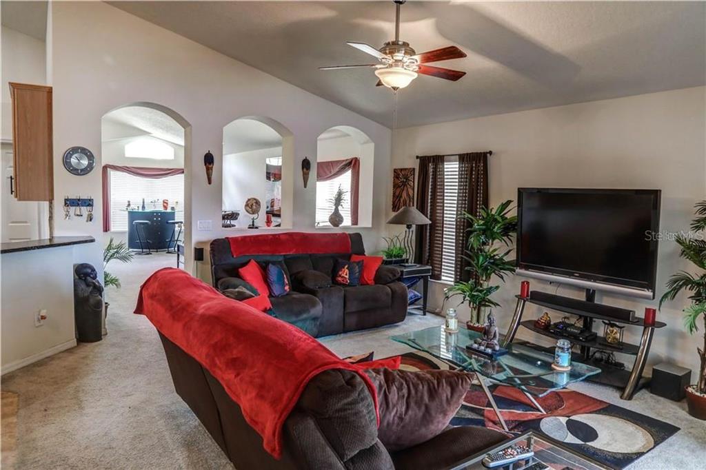 A living room features brown sofas, a glass coffee table, and arched wall cutouts — 1521 ECHO LAKE COURT, ORLANDO, FL