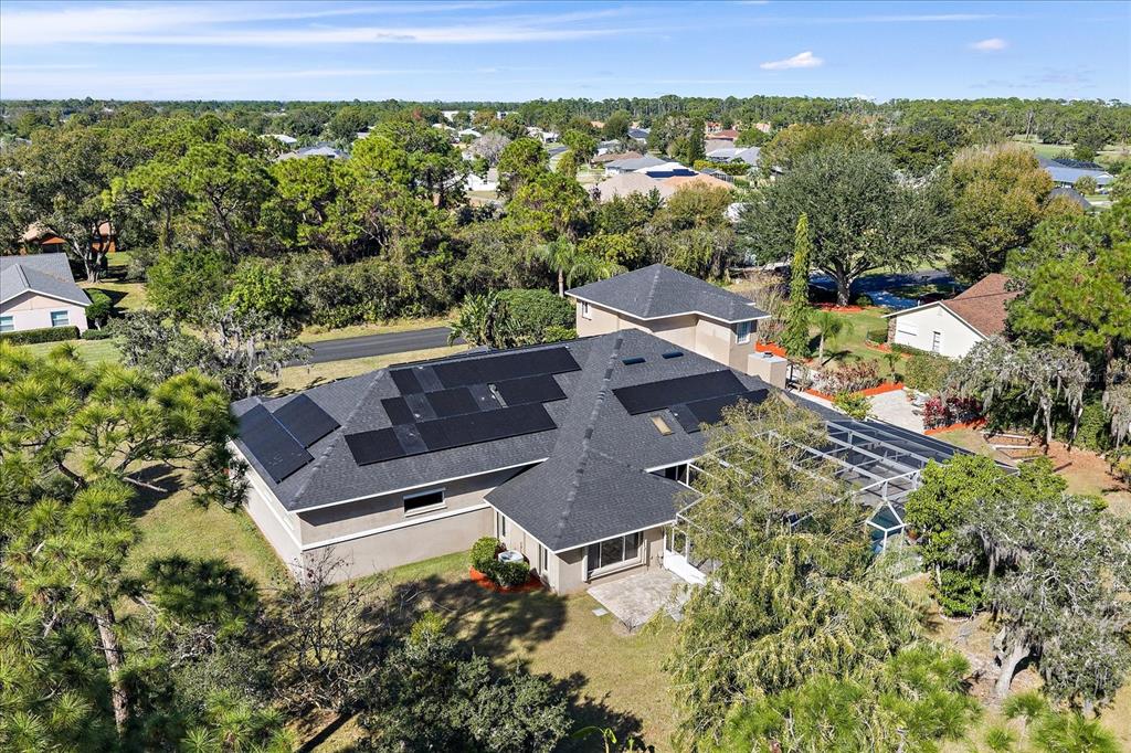 An aerial view shows a house with solar panels on the roof and a screened-in pool — 3416 SUNRISE DRIVE, SEBRING, FL