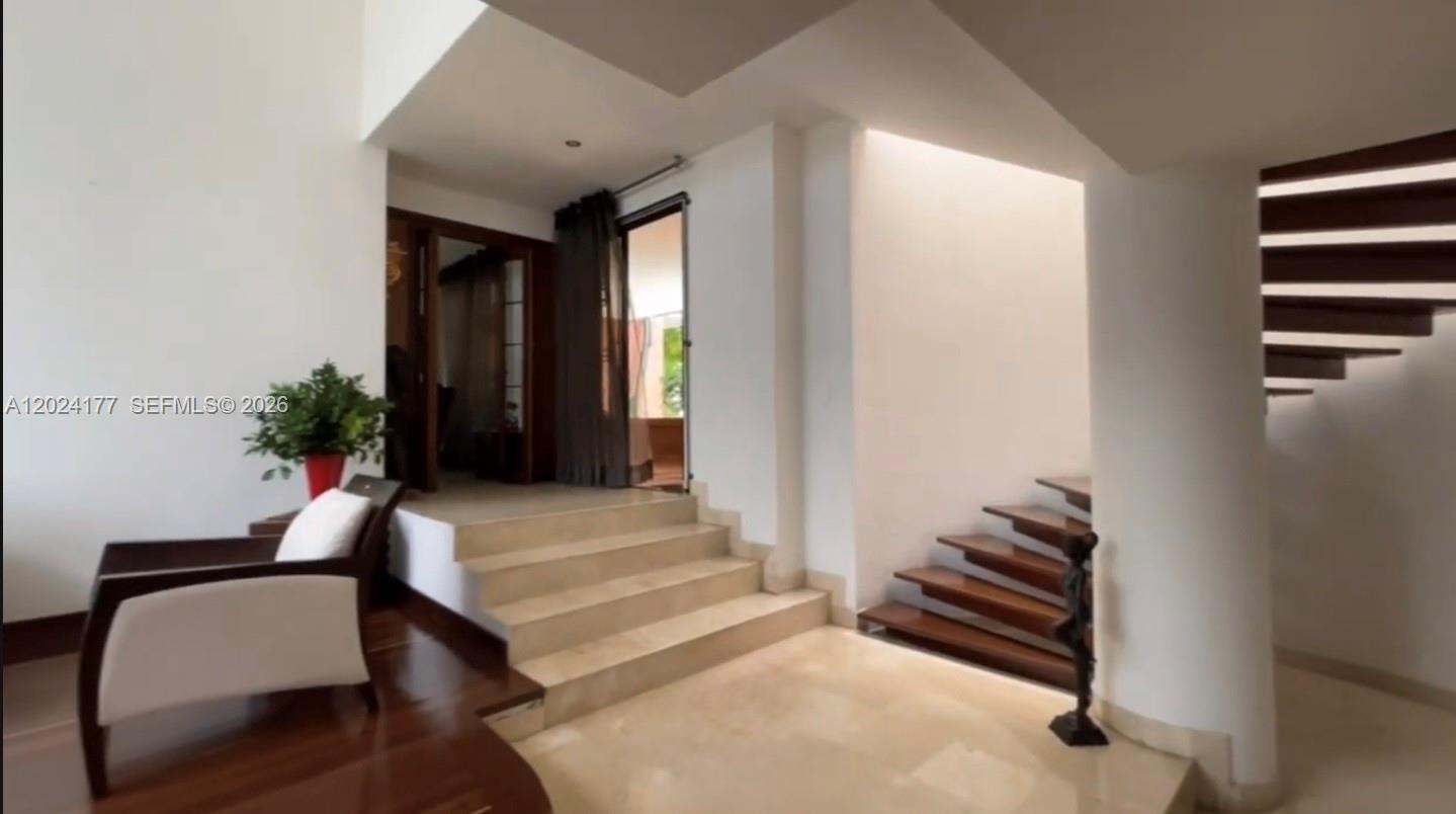 A modern interior features a raised entryway with stairs, a wooden staircase, and a chair — 17 # 7- 120 Carrera, FL 0000, FL