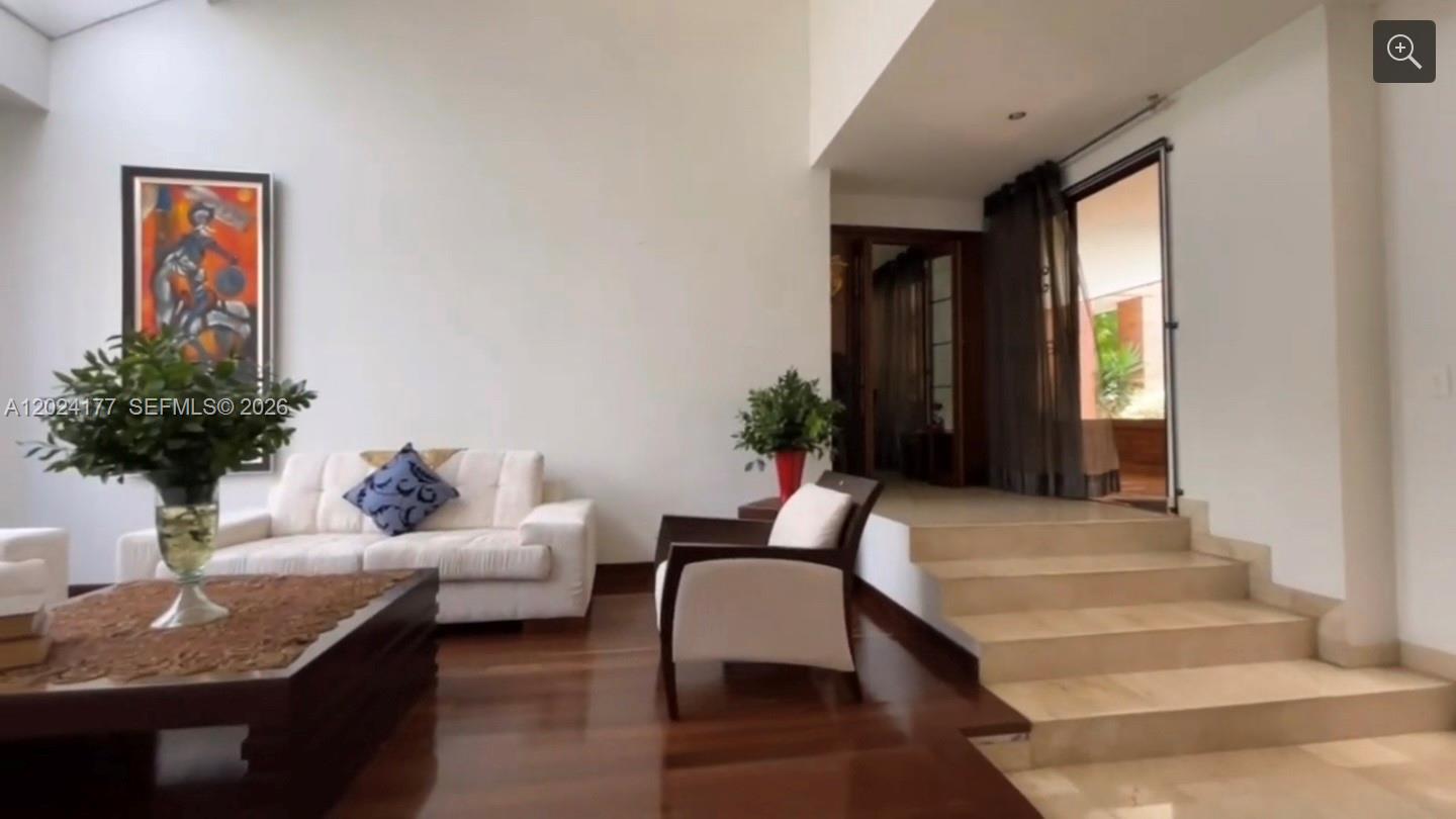 A living room features white walls, dark wood flooring, a sofa, and stairs leading upward — 17 # 7- 120 Carrera, FL 0000, FL