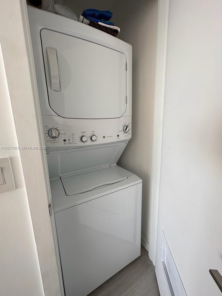 A white stacked washer and dryer unit is installed in a small laundry closet — 480 NE 31st St # 1902, Miami FL 33137, MIAMI, FL