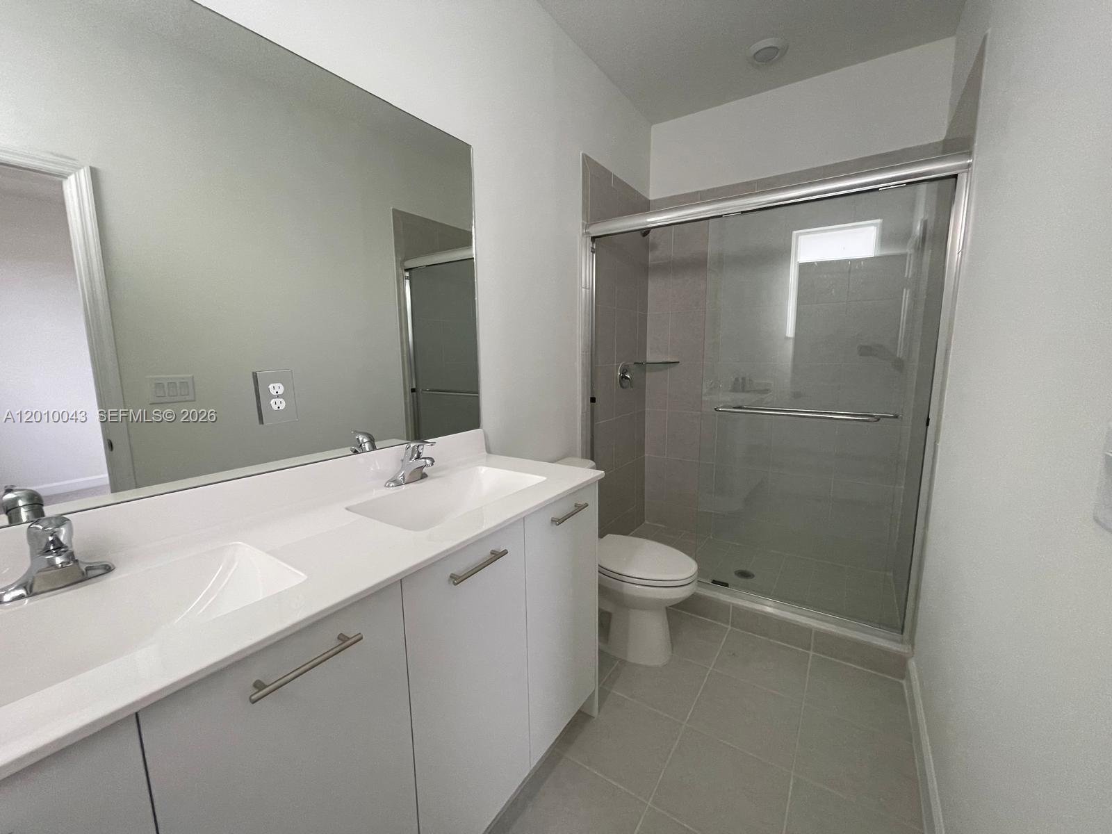 A modern bathroom features a double vanity with white cabinets and a glass-enclosed shower — 12372 NW 23rd Ct # 12372, Miami FL 33167, MIAMI, FL