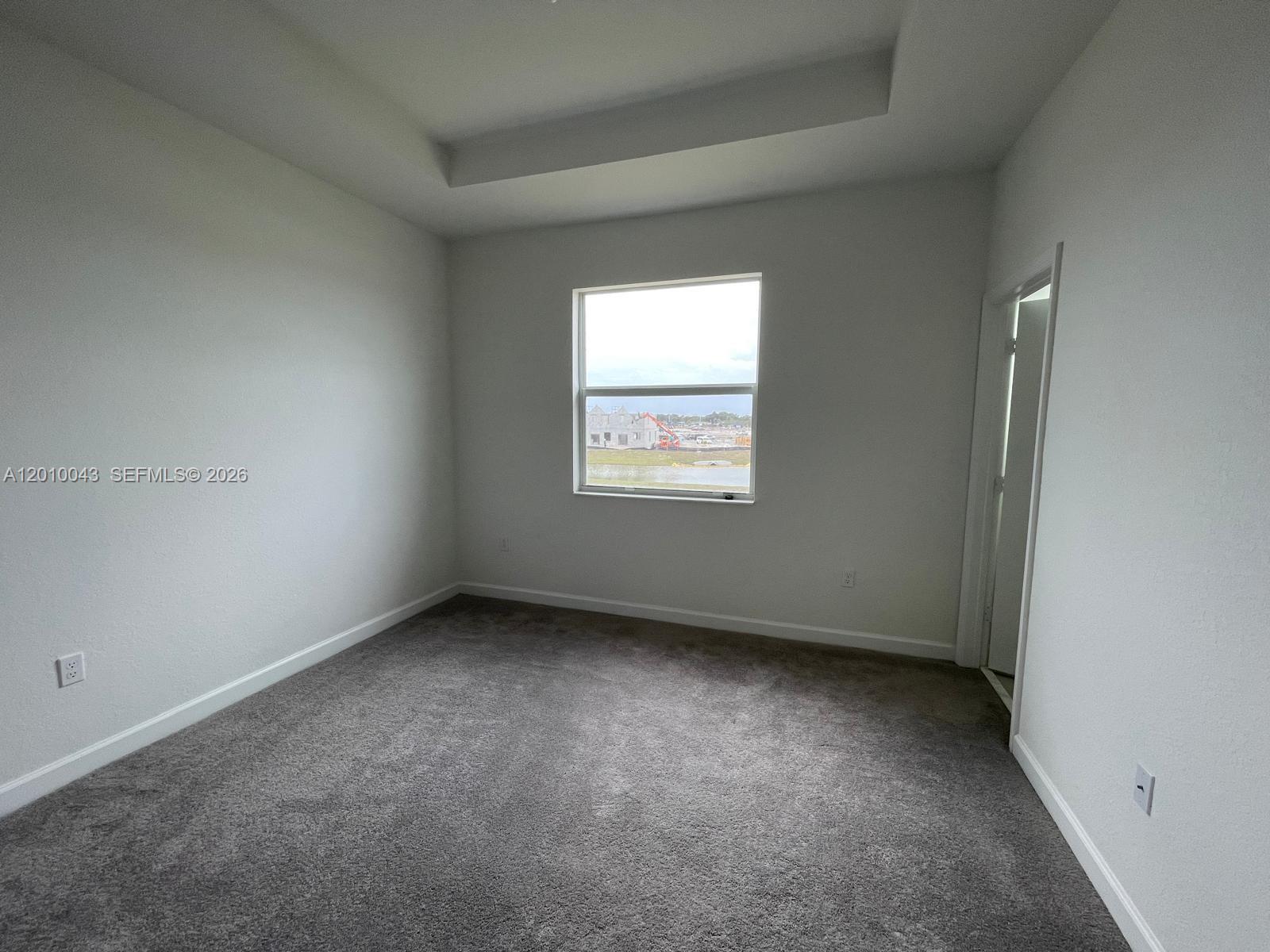 An empty bedroom features gray carpeting, white walls, a tray ceiling, and a single window — 12372 NW 23rd Ct # 12372, Miami FL 33167, MIAMI, FL