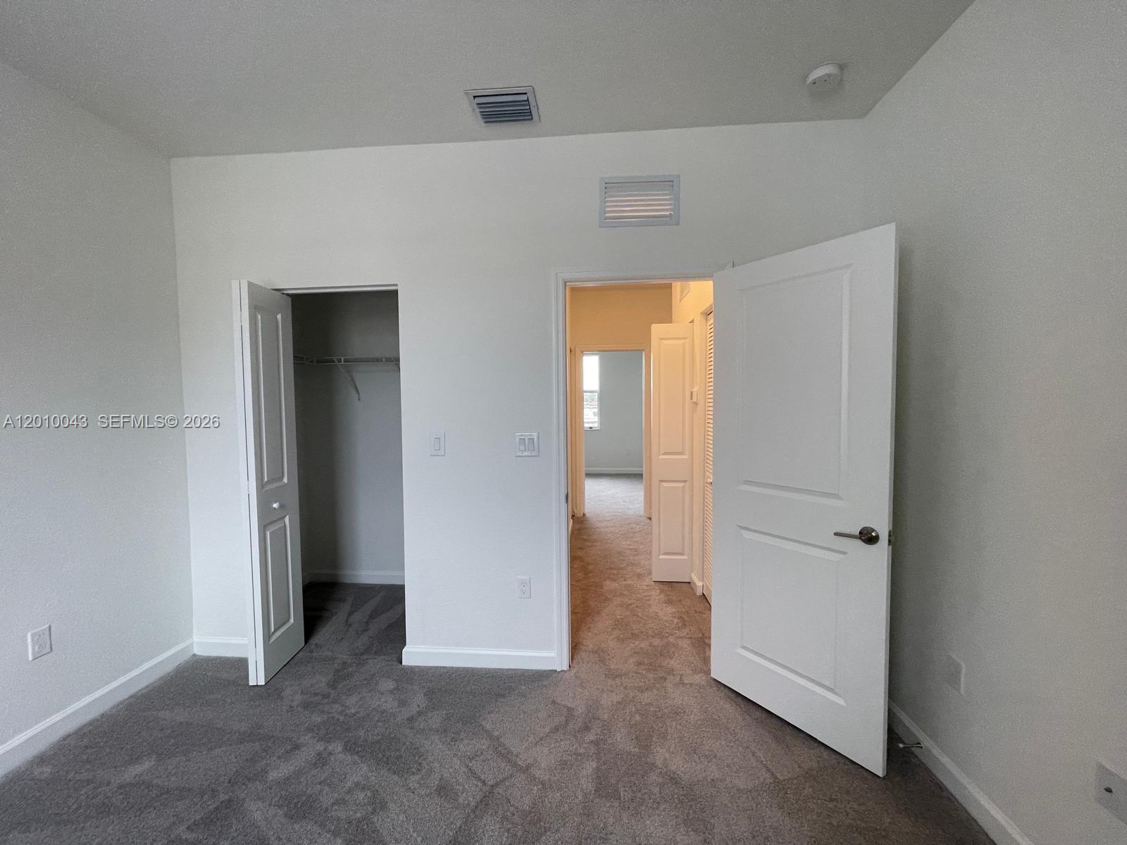 A bedroom features gray carpeting, white walls, an open closet, and an open doorway — 12372 NW 23rd Ct # 12372, Miami FL 33167, MIAMI, FL