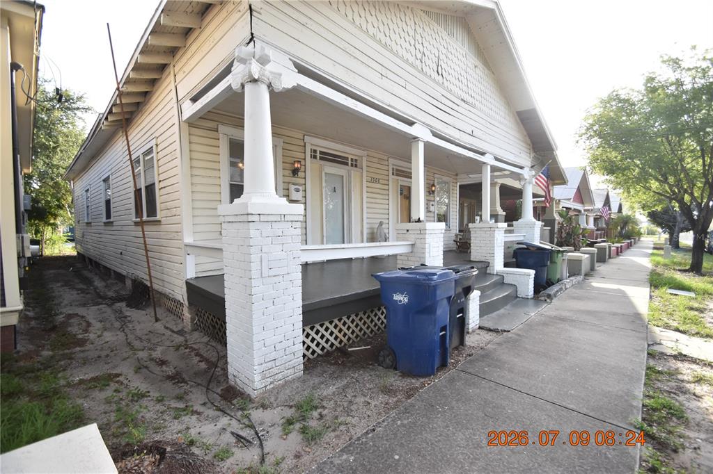 A single-story house with a white-painted porch featuring brick columns and wooden siding — 1908 E 15TH AVENUE UNIT A, TAMPA, FL
