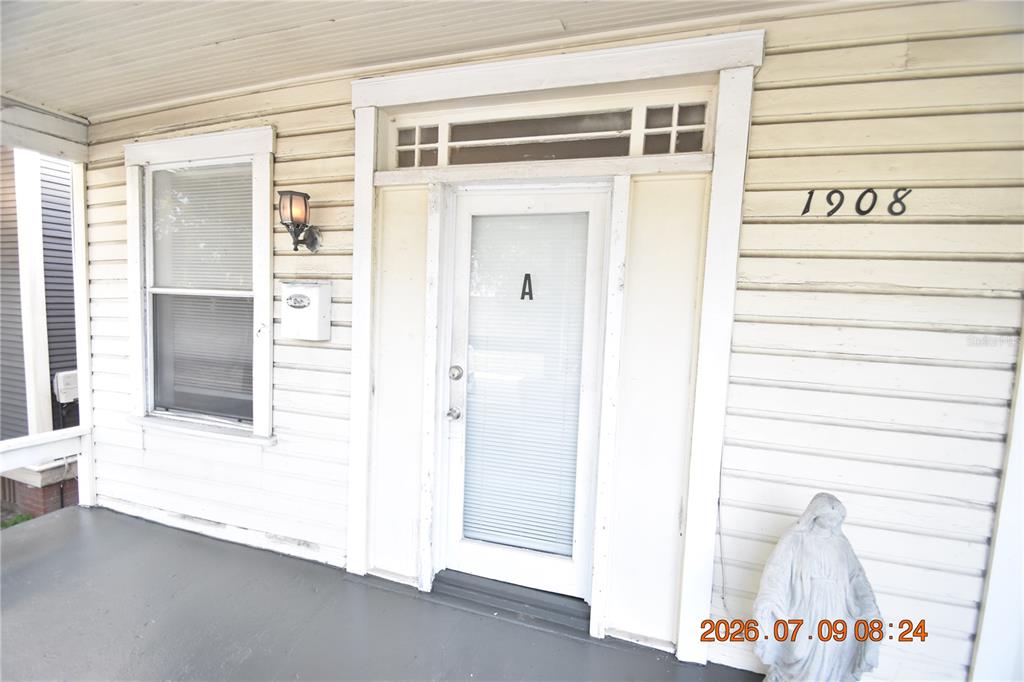 A white-sided house exterior features a front porch, a door marked A, and a statue — 1908 E 15TH AVENUE UNIT A, TAMPA, FL