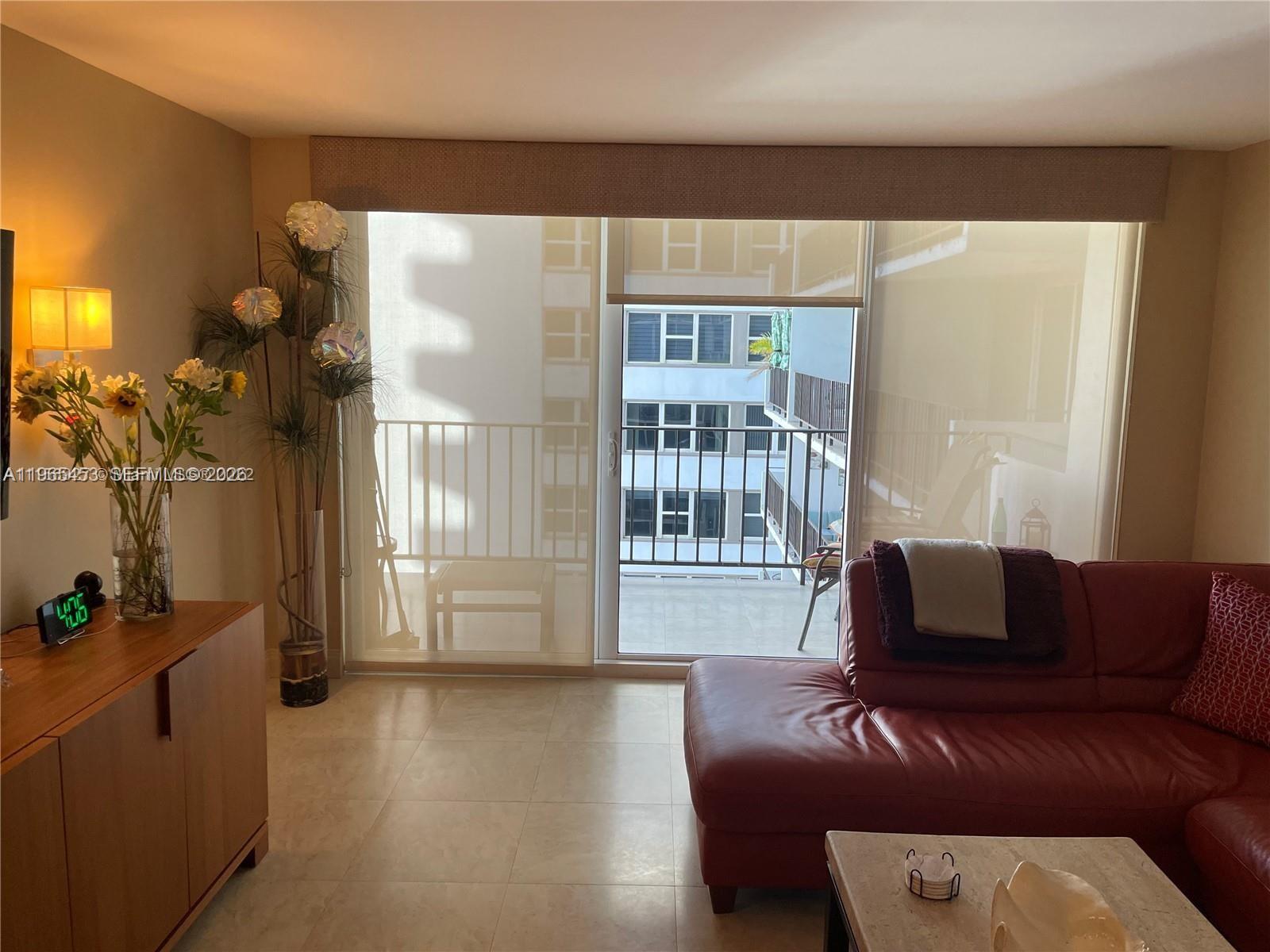A living room features a red leather sofa, tile flooring, and a balcony with exterior views — 2030 S Ocean Dr # 1404, Hallandale Beach FL 33009, HALLANDALE BEACH, FL