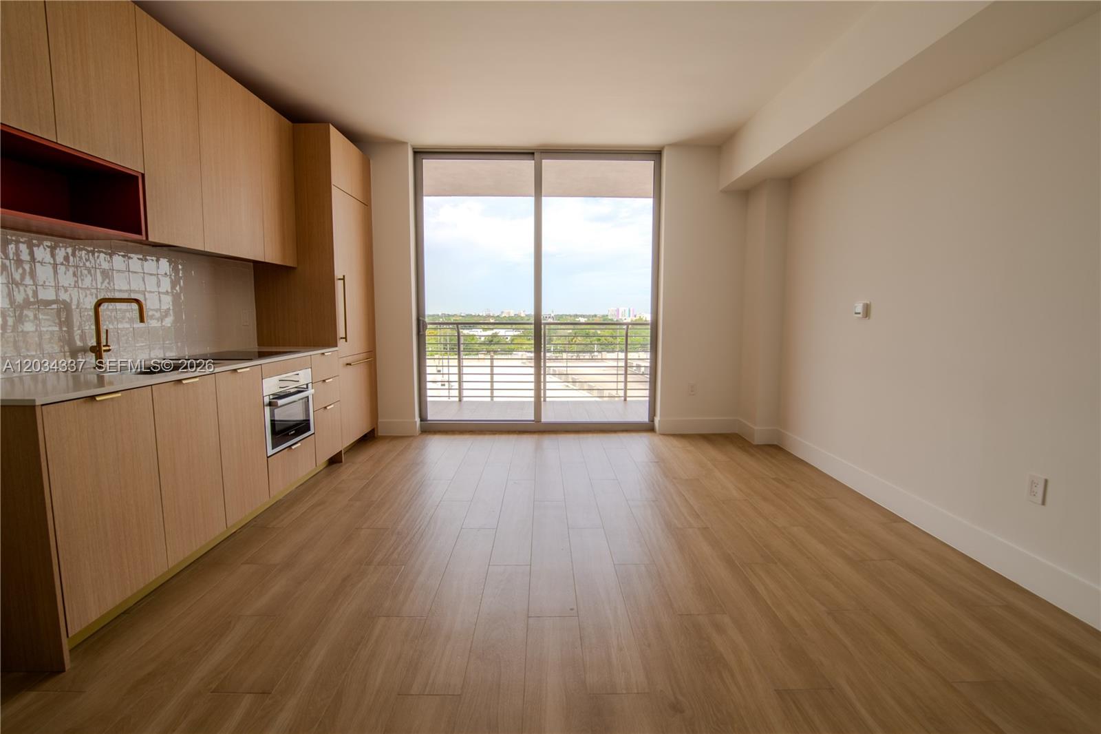 A modern kitchen with light wood cabinetry and a balcony overlooking a city view — 90 NE 32nd St # 824, Miami FL 33137, MIAMI, FL