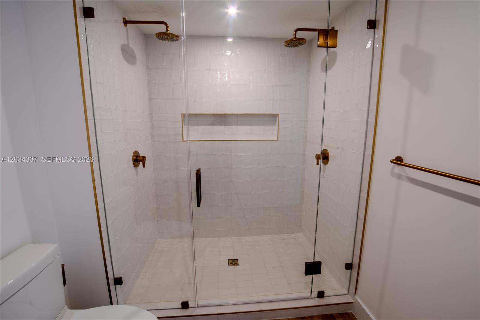 A walk-in shower features white tiled walls, gold fixtures, and a glass enclosure — 90 NE 32nd St # 824, Miami FL 33137, MIAMI, FL