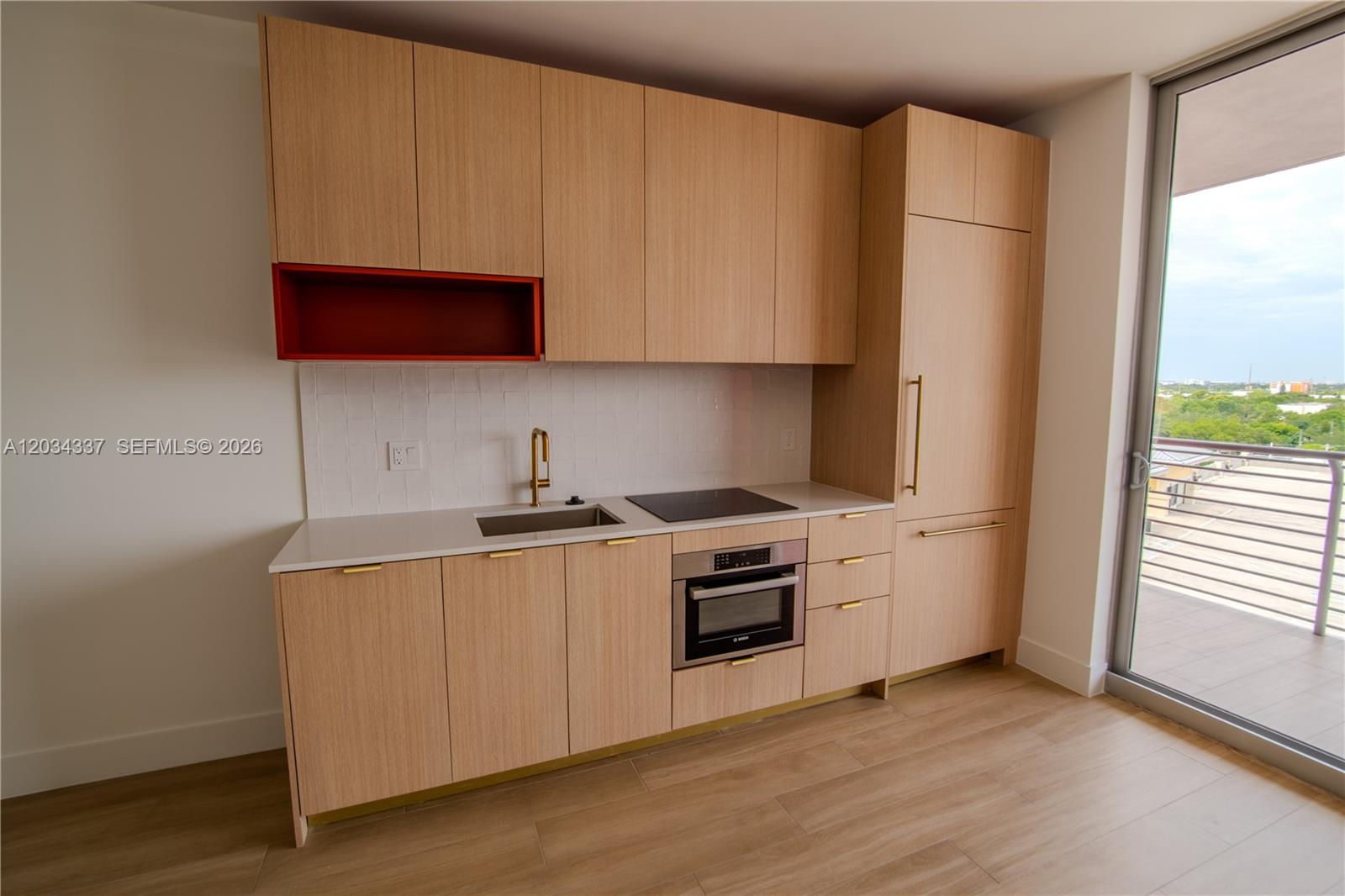 A modern kitchen features light wood cabinets, a red open shelf, and a balcony view — 90 NE 32nd St # 824, Miami FL 33137, MIAMI, FL