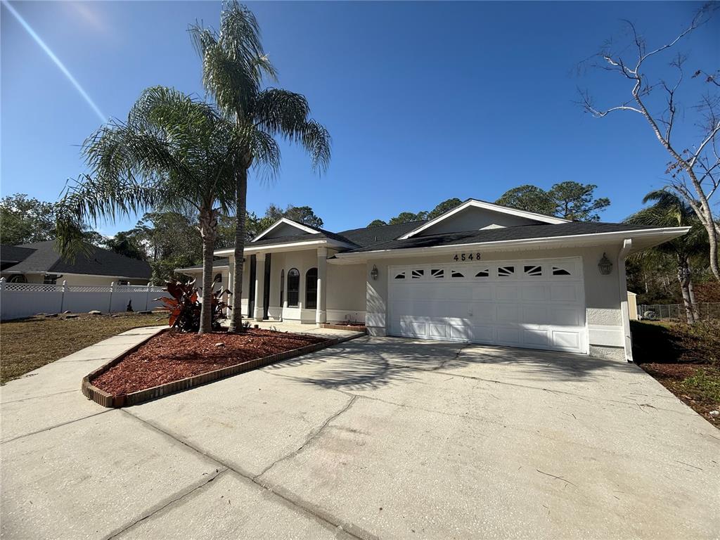 A single-story house with a white stucco exterior, a two-car garage, and a palm tree — 4548 YORKSHIRE LANE, KISSIMMEE, FL