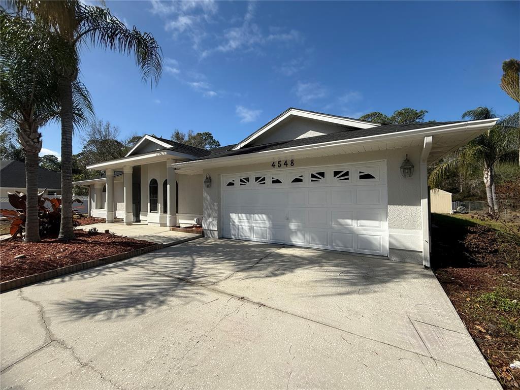 A single-story house with a white stucco exterior, a two-car garage, and a palm tree — 4548 YORKSHIRE LANE, KISSIMMEE, FL