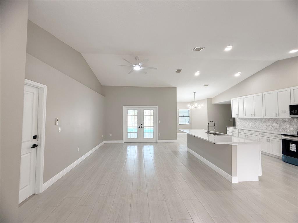 A bright open-concept kitchen and living area with white cabinets, an island, and light flooring — 4548 YORKSHIRE LANE, KISSIMMEE, FL