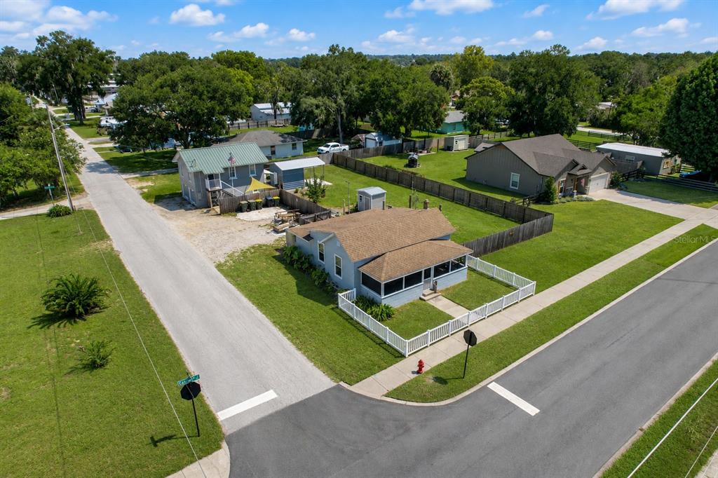 An aerial view shows a light blue house with a screened porch and fenced yard — 321 CASSADY STREET, UMATILLA, FL