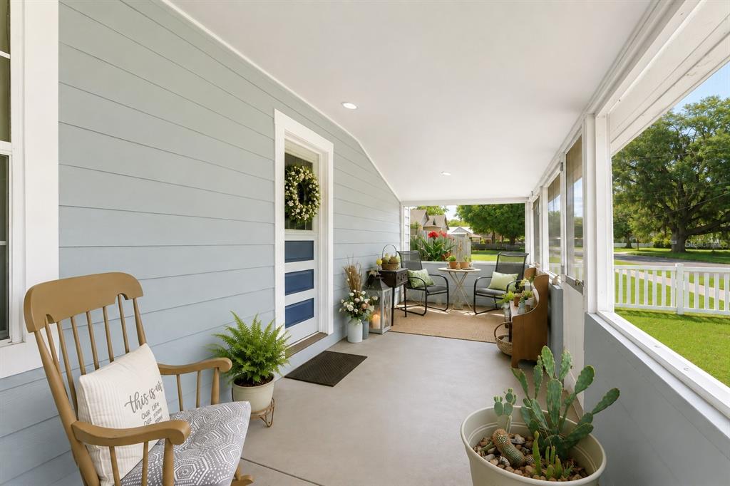 A covered porch features light blue siding, a rocking chair, and a screened-in seating area — 321 CASSADY STREET, UMATILLA, FL